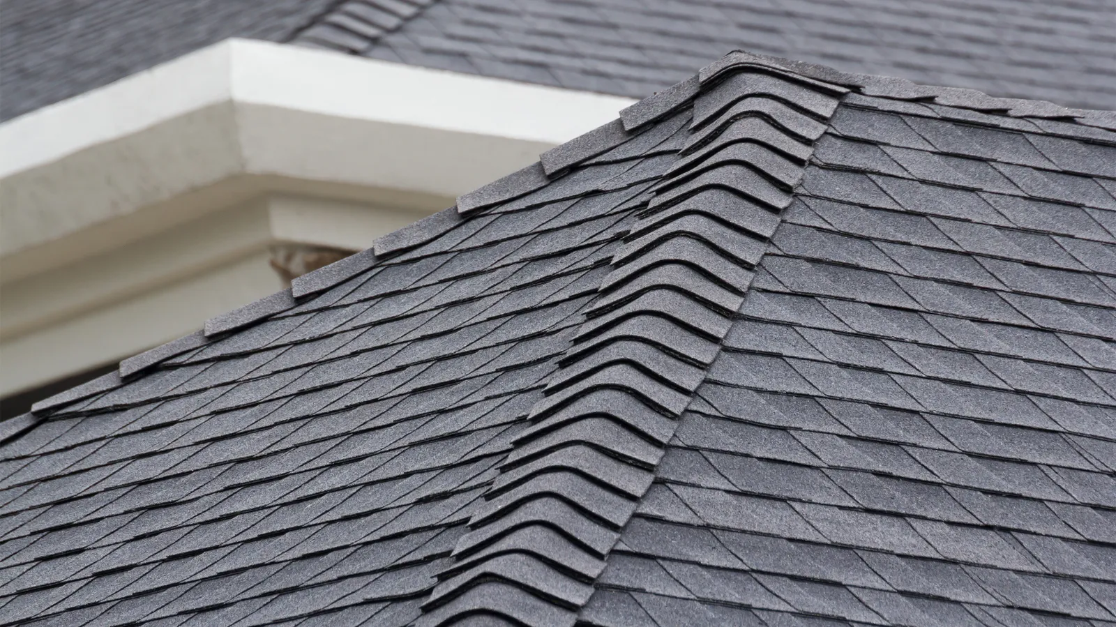 Gray shingle roof hip lined with ridge cap shingles