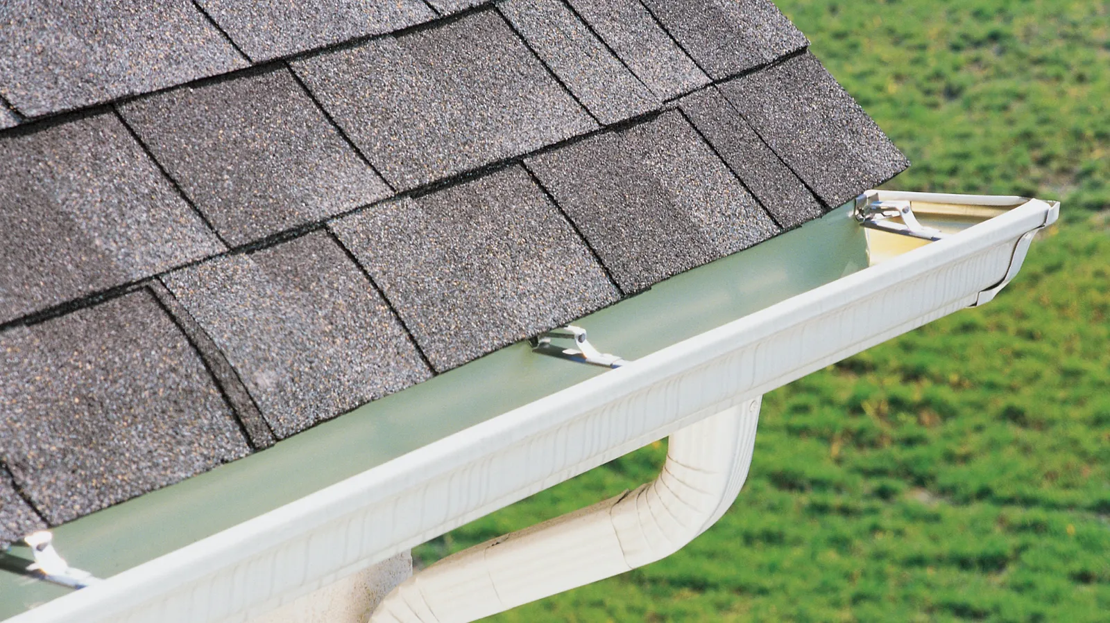 Downspout and gutter meeting at a shingle roof corner